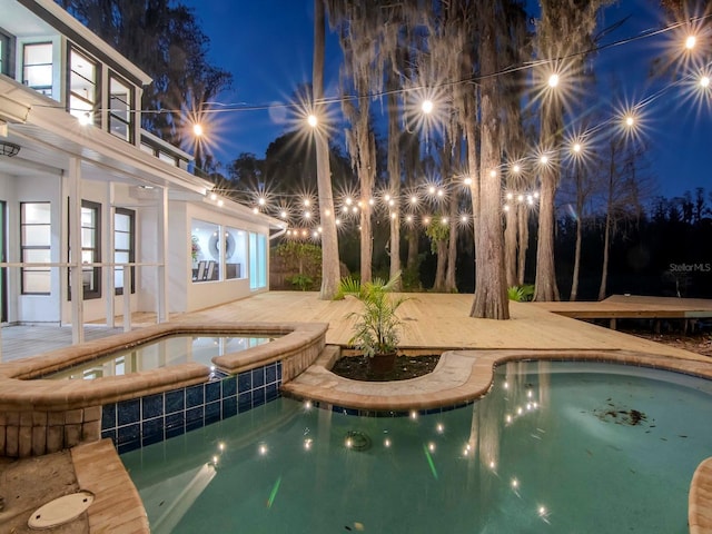 pool at twilight with an outdoor pool, a patio, and an in ground hot tub