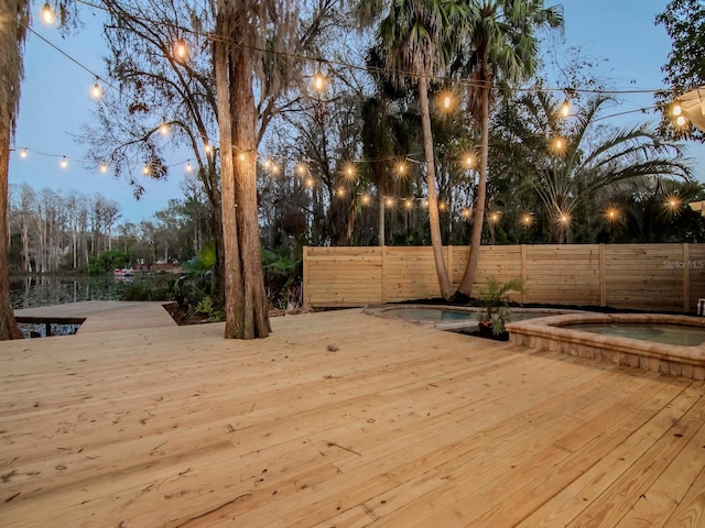 exterior space featuring an in ground hot tub, fence, and a wooden deck