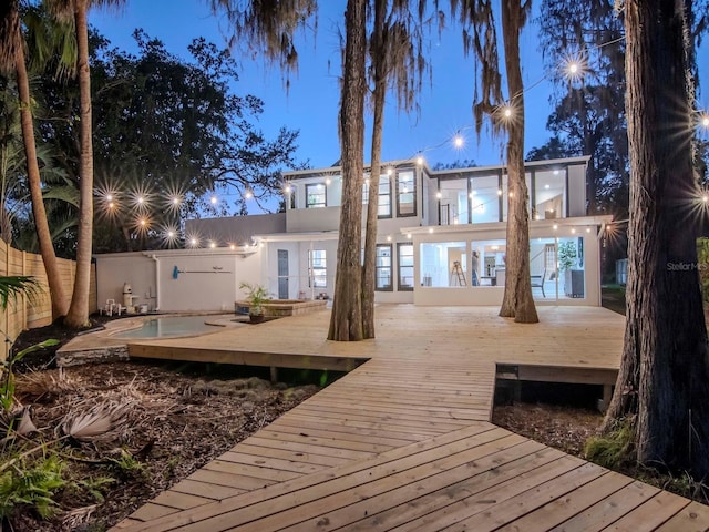 back of house with a deck, fence, and stucco siding