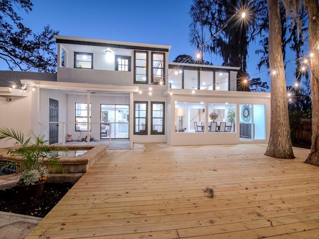 back of property with a wooden deck and stucco siding