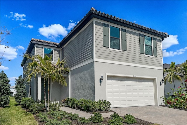 view of front of house with stucco siding, decorative driveway, a garage, and a tile roof