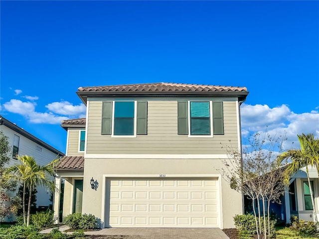 view of front of property featuring stucco siding, an attached garage, driveway, and a tile roof