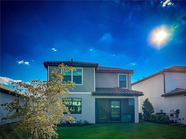 back of property with a tile roof and a yard