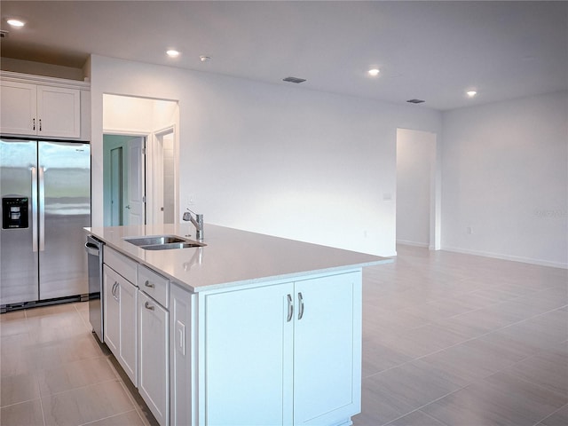 kitchen featuring a center island with sink, recessed lighting, a sink, white cabinets, and appliances with stainless steel finishes