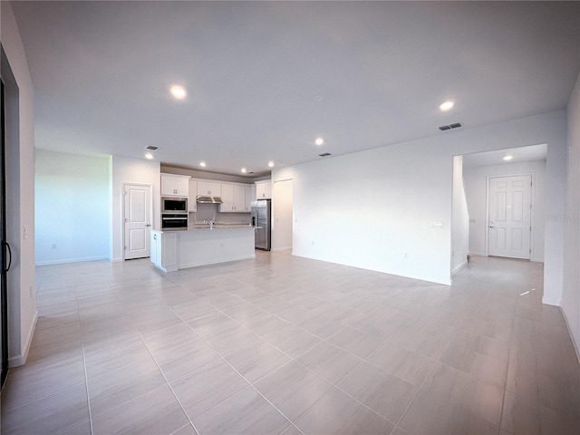 unfurnished living room with visible vents, recessed lighting, baseboards, and a sink