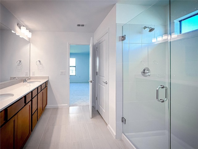 bathroom with double vanity, a stall shower, visible vents, and a sink