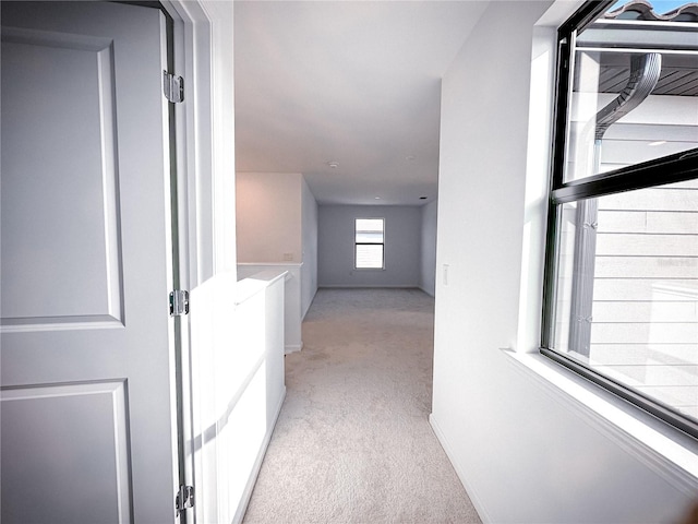 hallway featuring baseboards and light carpet