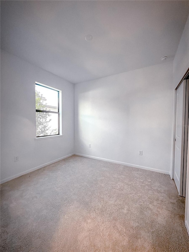 unfurnished room featuring light colored carpet and baseboards