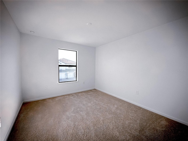 carpeted empty room with baseboards