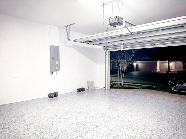 garage featuring electric panel, concrete block wall, and a garage door opener