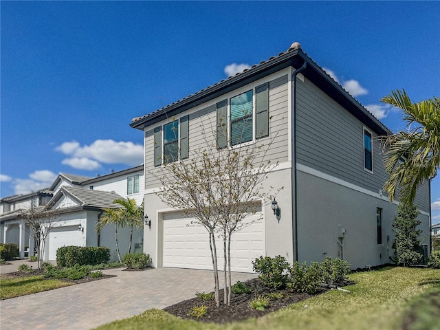 view of front of home with stucco siding, decorative driveway, and an attached garage