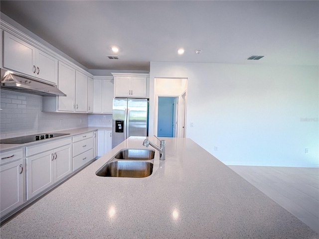 kitchen with visible vents, under cabinet range hood, stainless steel refrigerator with ice dispenser, black electric cooktop, and a sink