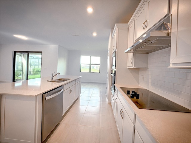 kitchen featuring under cabinet range hood, decorative backsplash, appliances with stainless steel finishes, white cabinetry, and a sink