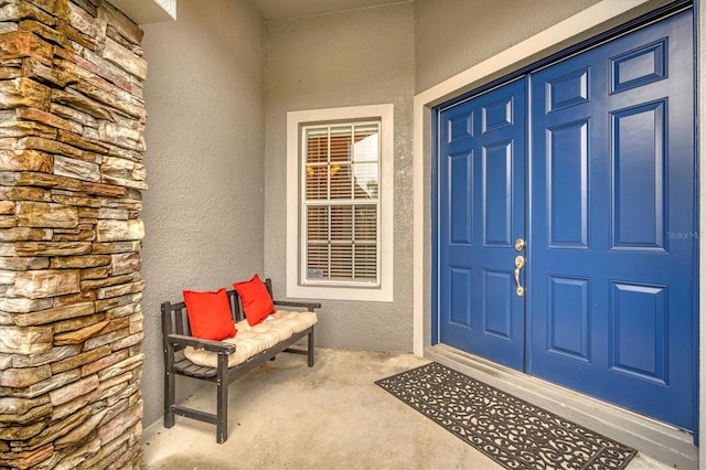 view of exterior entry featuring covered porch and stucco siding