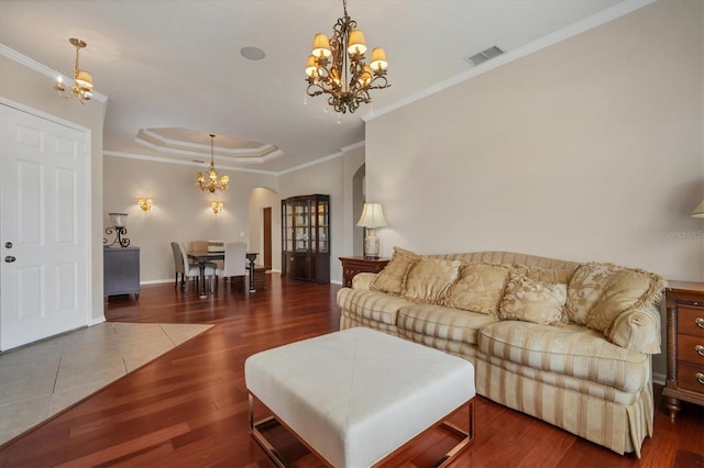 living room with arched walkways, a raised ceiling, visible vents, an inviting chandelier, and wood finished floors