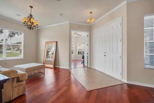 entrance foyer with ornamental molding, visible vents, baseboards, and wood finished floors