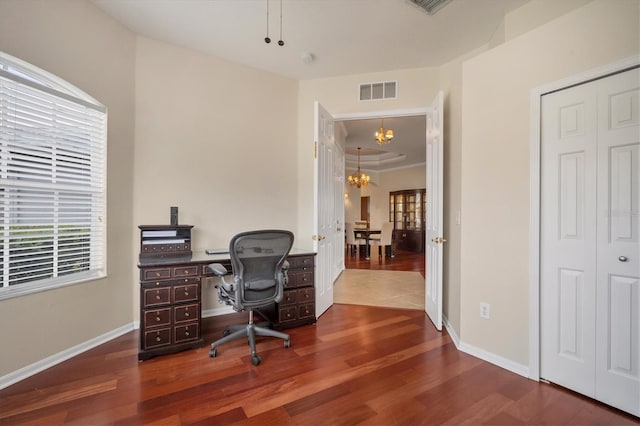 office space with a chandelier, visible vents, baseboards, and wood finished floors