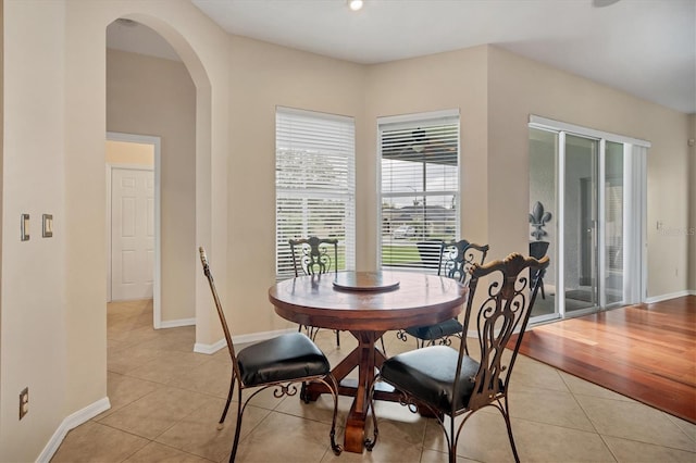 dining area with light tile patterned floors, baseboards, and arched walkways