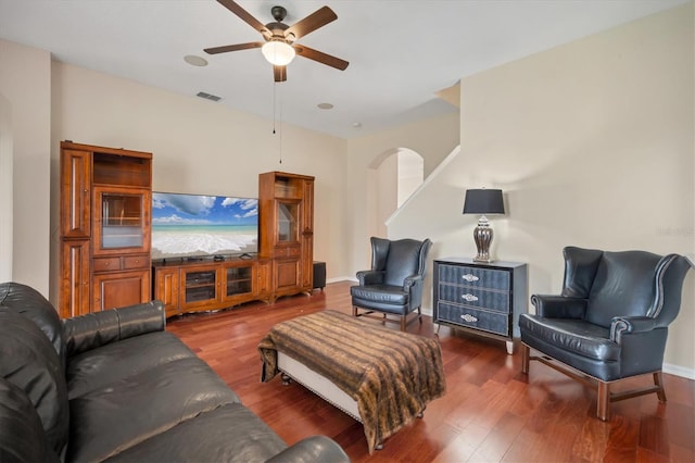 living room featuring arched walkways, ceiling fan, wood finished floors, visible vents, and baseboards