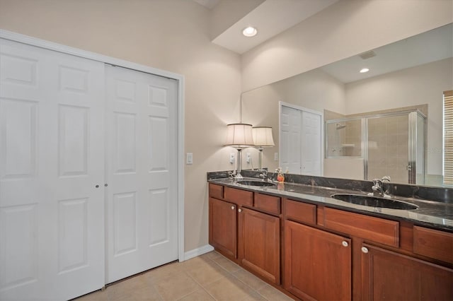 bathroom with double vanity, a shower stall, a sink, and tile patterned floors