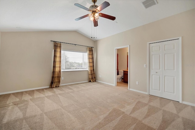 unfurnished bedroom featuring lofted ceiling, visible vents, baseboards, carpet, and ensuite bath