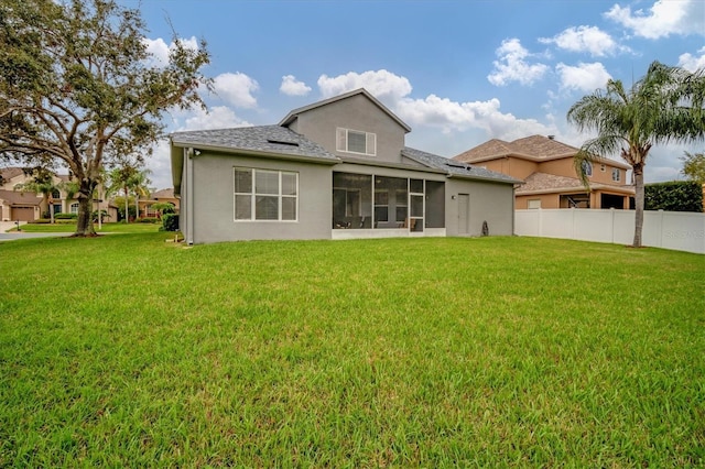 back of property featuring a sunroom, fence, and a lawn