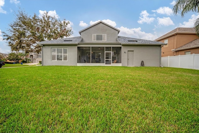 back of property with a sunroom, a lawn, and fence