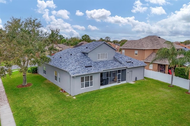 back of house with roof with shingles, a lawn, fence, and stucco siding