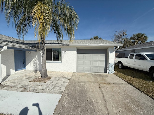 view of front facade with a garage, driveway, a shingled roof, and stucco siding