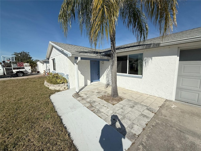 view of front of house with a shingled roof, a front lawn, and stucco siding