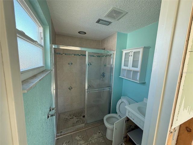 full bathroom featuring a textured ceiling, toilet, visible vents, tile patterned floors, and a stall shower