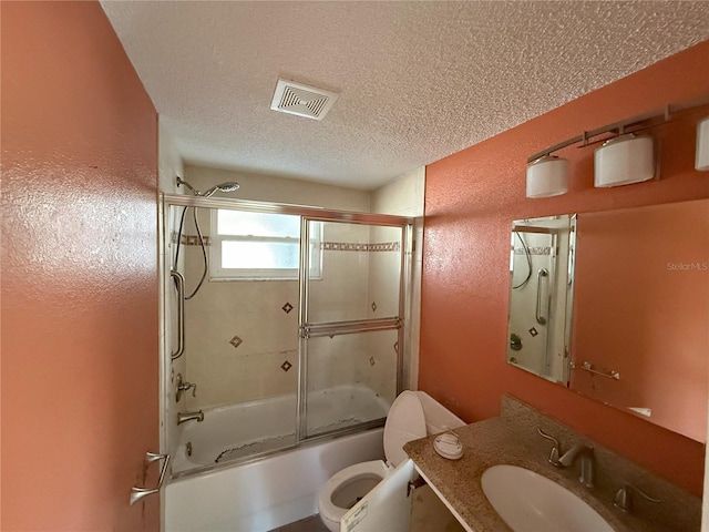 bathroom with visible vents, bath / shower combo with glass door, toilet, a textured ceiling, and vanity