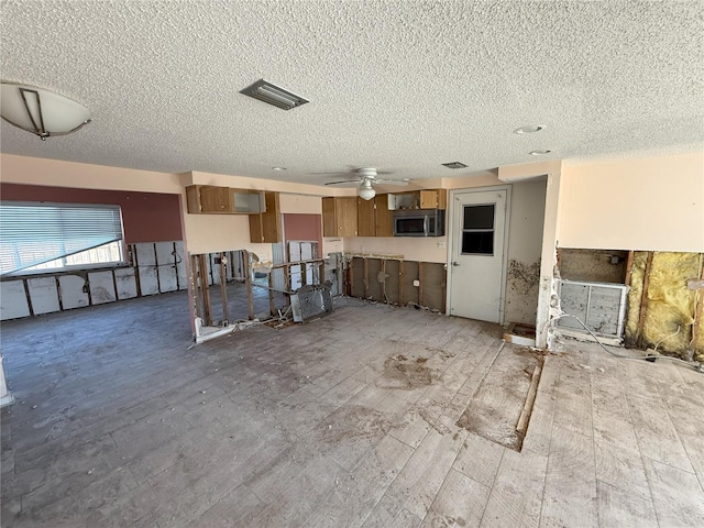 unfurnished living room featuring a textured ceiling, visible vents, and a ceiling fan