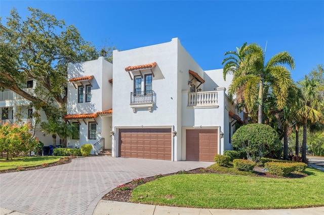 view of front of house with decorative driveway, an attached garage, a balcony, and stucco siding