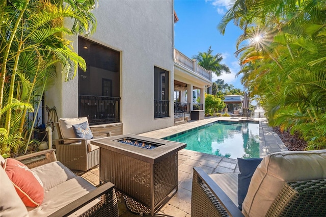 view of pool featuring a fenced in pool, an outdoor living space with a fire pit, and a patio