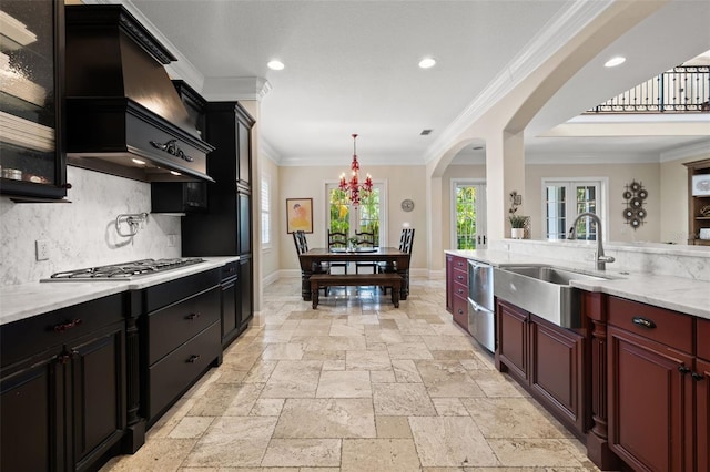 kitchen with stone tile floors, stainless steel appliances, backsplash, ornamental molding, and a sink