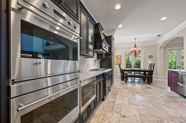 kitchen with arched walkways, appliances with stainless steel finishes, crown molding, stone tile flooring, and backsplash