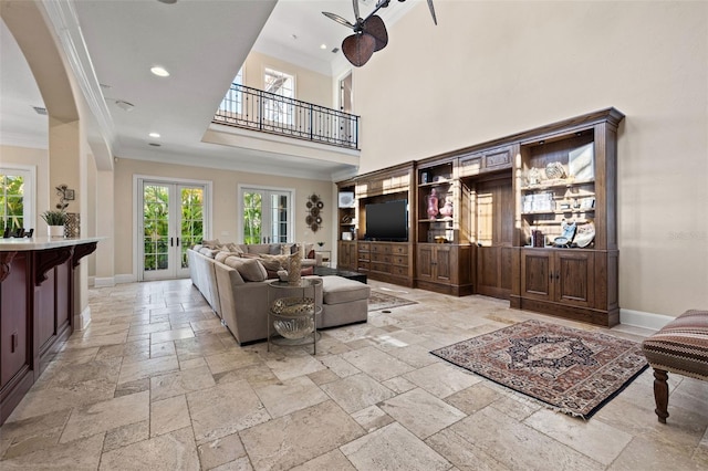 living area with ornamental molding, french doors, baseboards, and stone tile floors