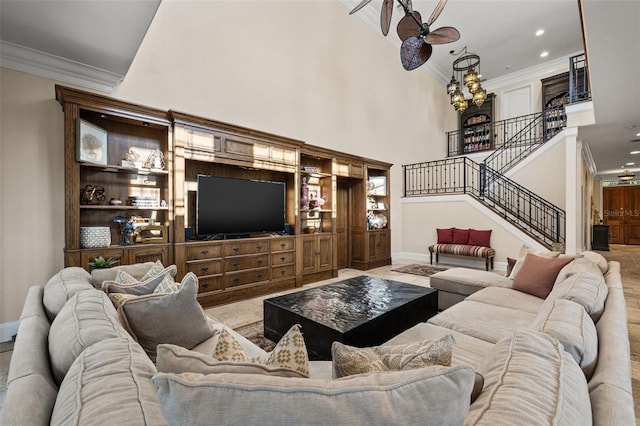 living area with ornamental molding, a towering ceiling, and stairs