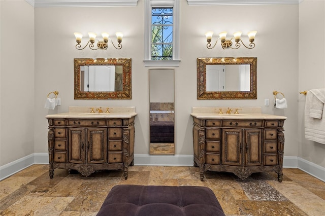 full bathroom with two vanities, baseboards, a sink, and stone tile floors