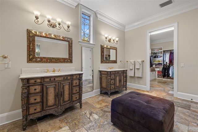 full bath featuring a sink, two vanities, baseboards, visible vents, and crown molding