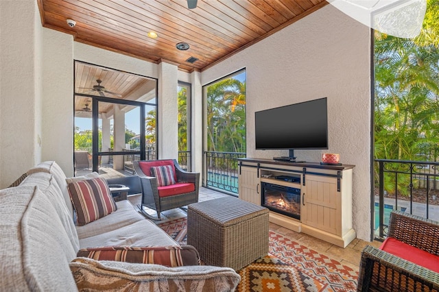 living room with a textured wall, a glass covered fireplace, wood ceiling, ceiling fan, and tile patterned flooring