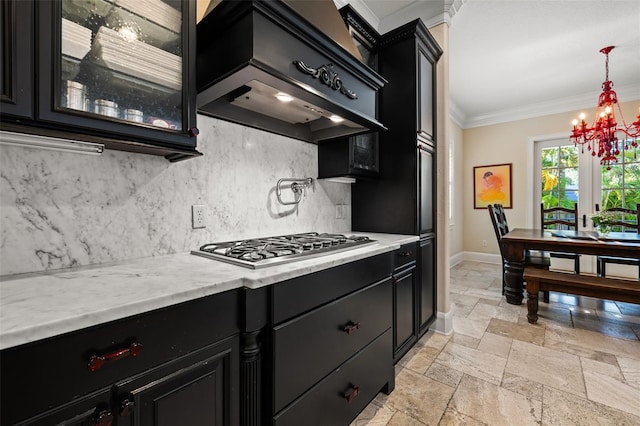 kitchen with stone tile floors, dark cabinetry, premium range hood, and ornamental molding