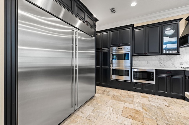 kitchen featuring stone tile floors, light countertops, visible vents, built in appliances, and dark cabinetry