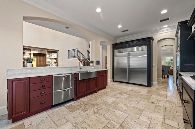 kitchen with arched walkways, stainless steel appliances, a sink, and light countertops