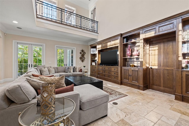 living room with a high ceiling, baseboards, french doors, stone tile flooring, and crown molding