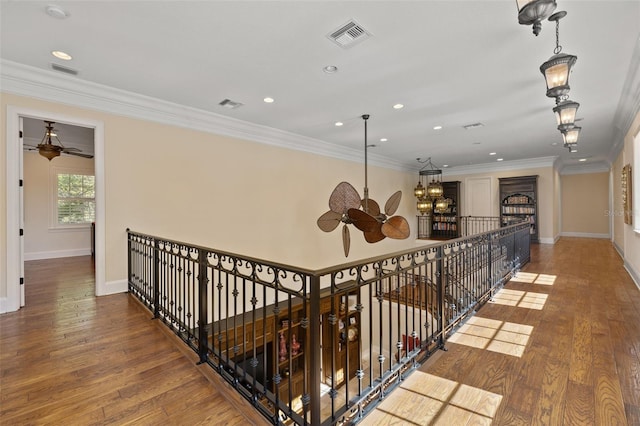 hall with visible vents, crown molding, and wood finished floors