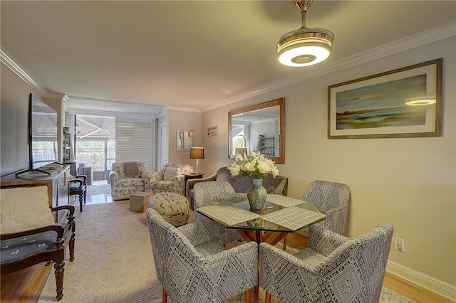 dining space featuring light wood-style flooring, baseboards, and crown molding