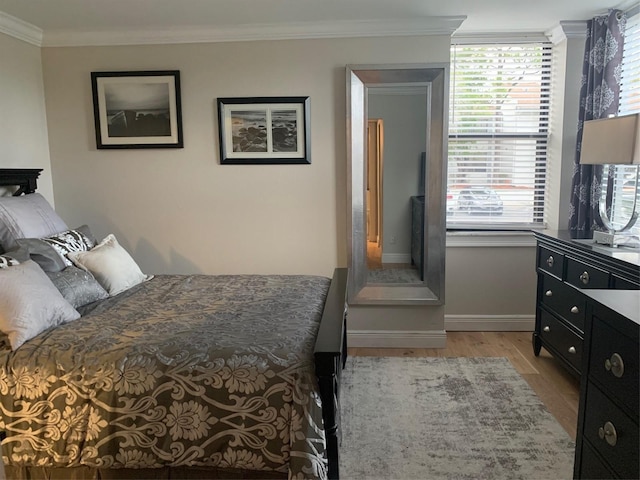 bedroom with ornamental molding, light wood-style flooring, and baseboards