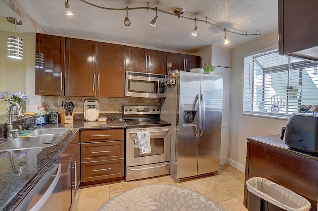 kitchen with a sink, appliances with stainless steel finishes, decorative backsplash, dark stone countertops, and pendant lighting